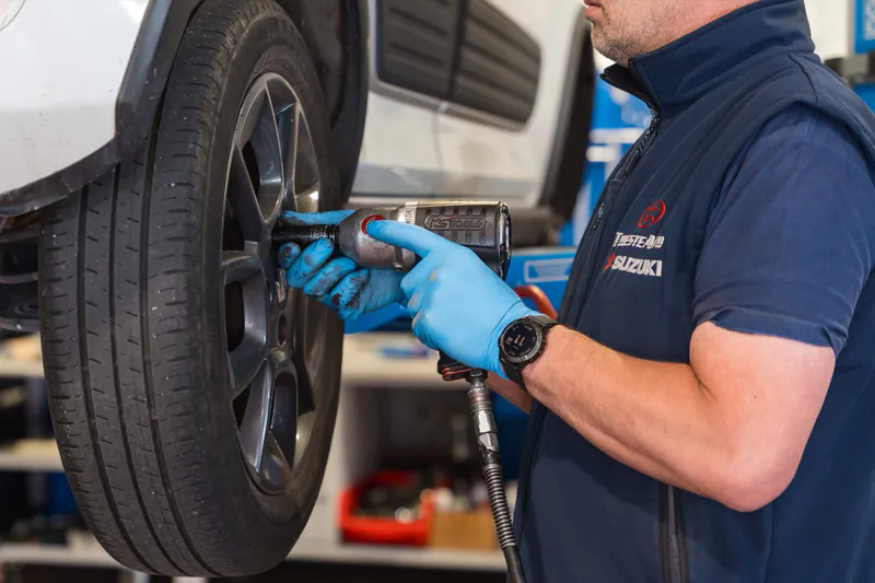 Tecnico Trieste Auto smonta la ruota di un'auto con avvitatore pneumatico nell'officina Suzuki di Muggia, servizio cambio gomme